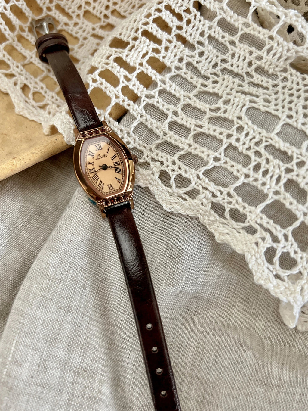 A classic watch with a brown leather strap and decorated with rhinestones.