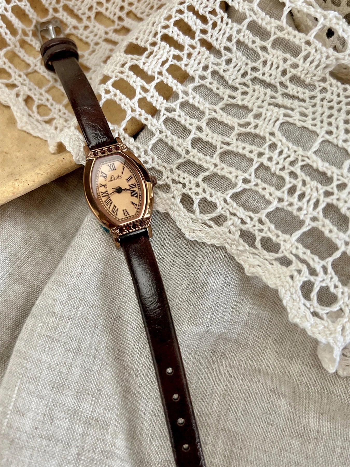 A classic watch with a brown leather strap and decorated with rhinestones.