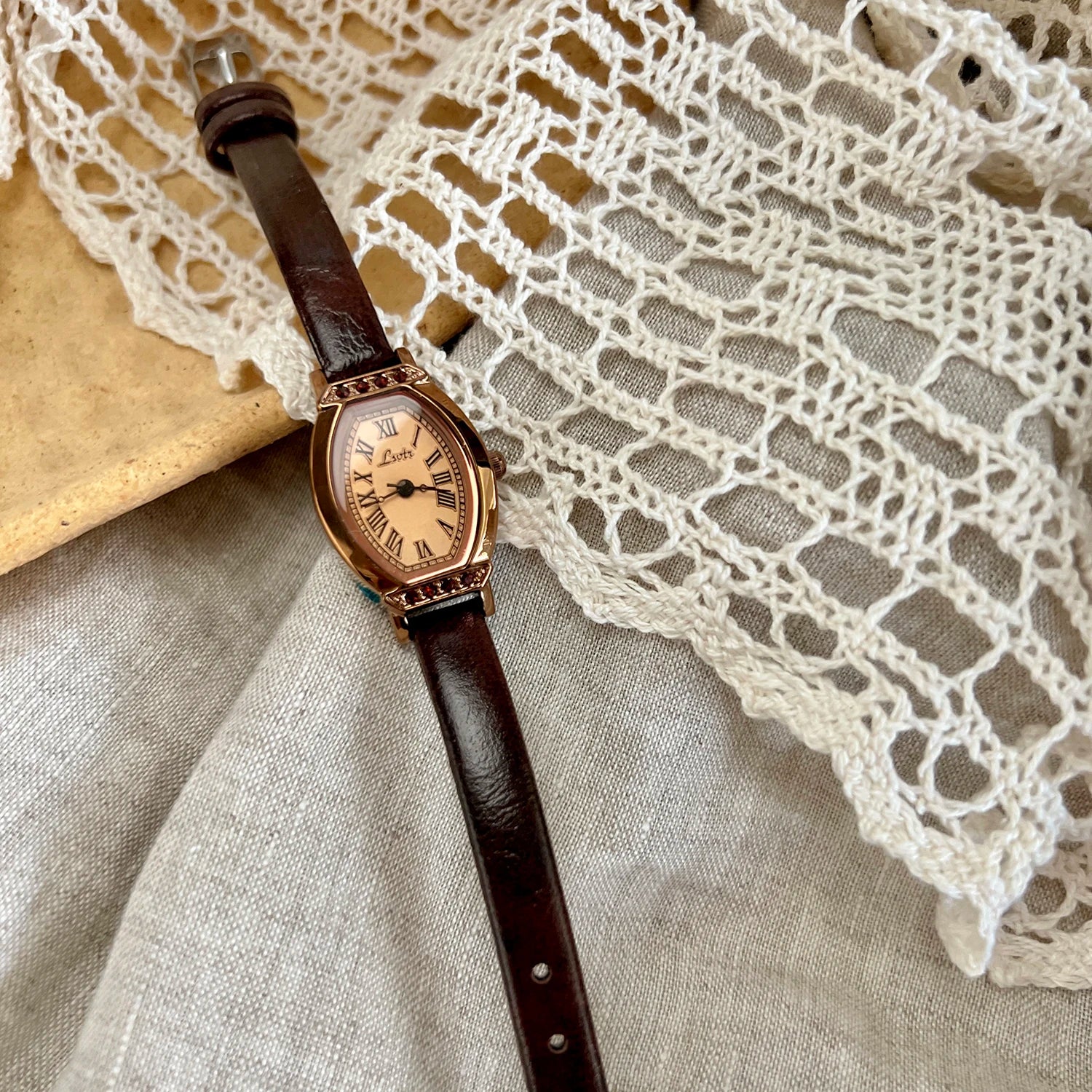 A classic watch with a brown leather strap and decorated with rhinestones.