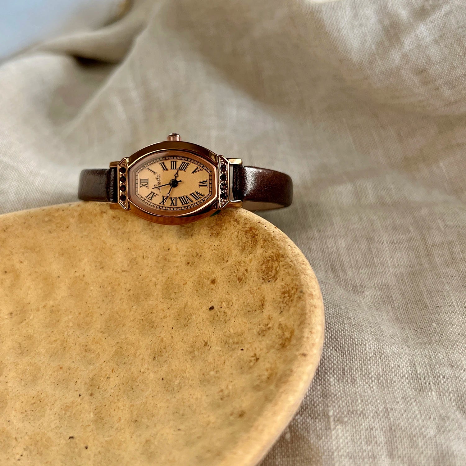 A classic watch with a brown leather strap and decorated with rhinestones.