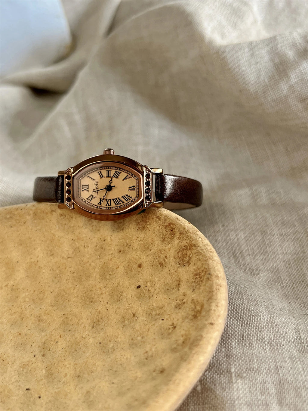 A classic watch with a brown leather strap and decorated with rhinestones.