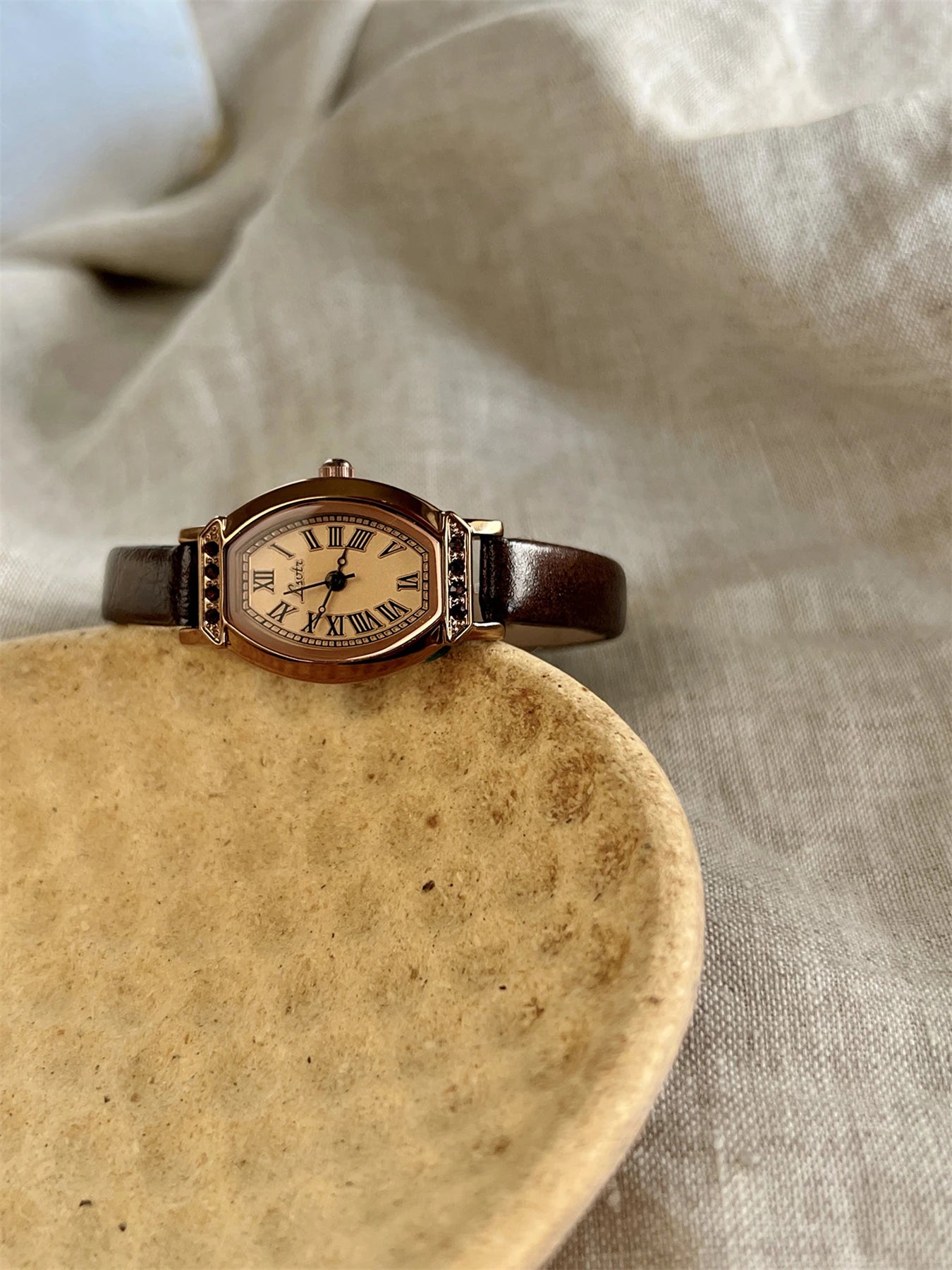 A classic watch with a brown leather strap and decorated with rhinestones.