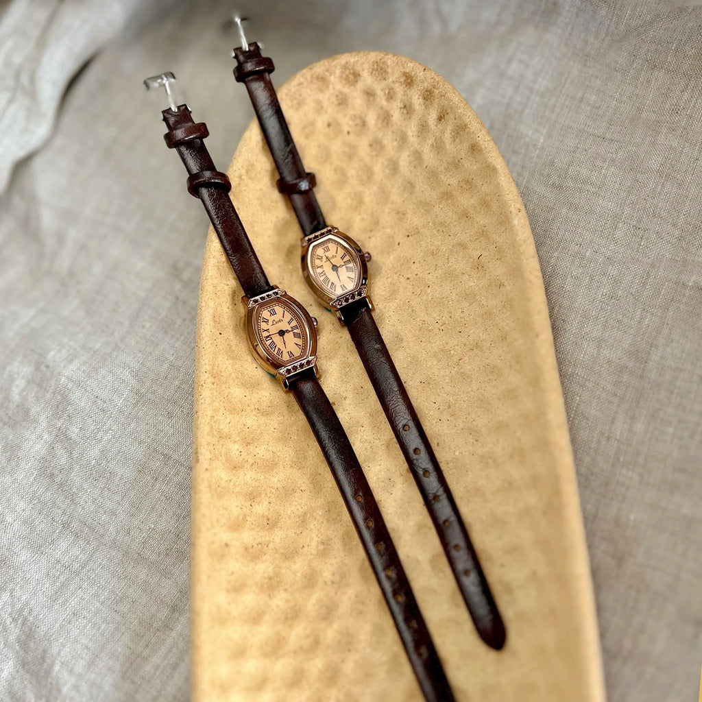 A classic watch with a brown leather strap and decorated with rhinestones.